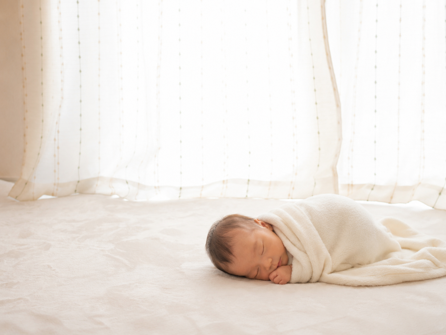 A peaceful newborn swaddled in a soft cream blanket, sleeping in gentle natural light by a window