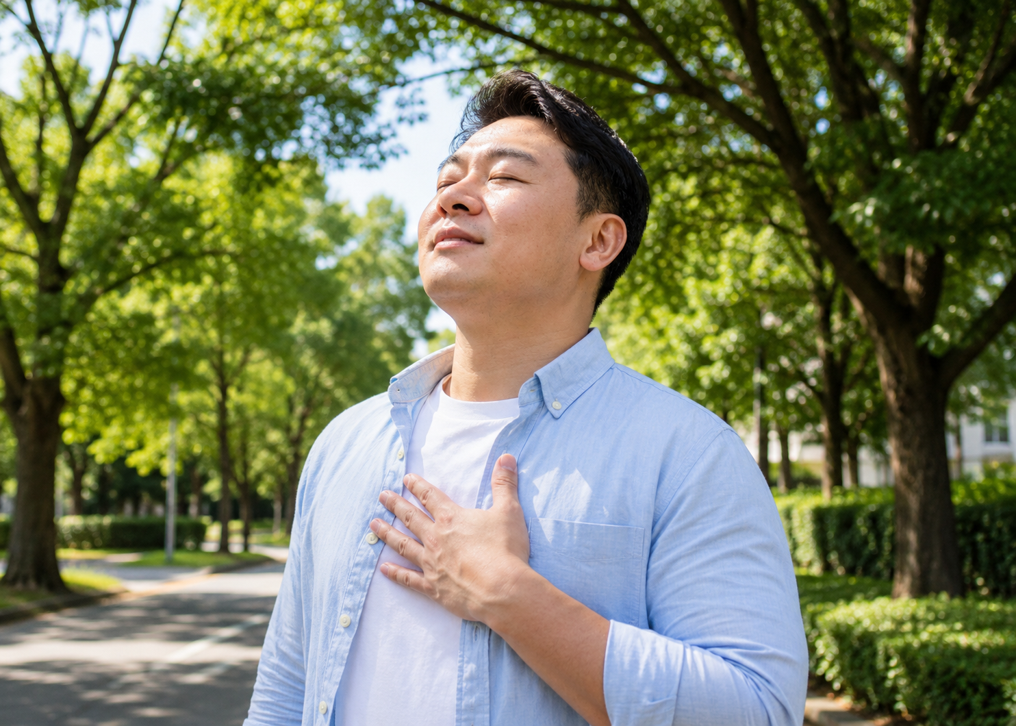 A person standing outdoors on a tree-lined street, hand on chest, breathing calmly in clean air